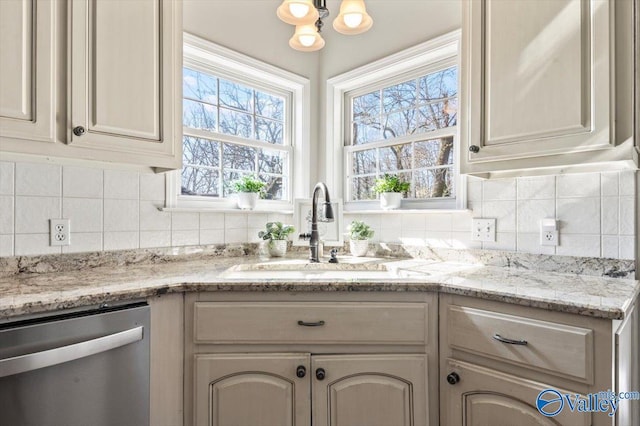 kitchen with tasteful backsplash, dishwasher, light stone counters, and a sink