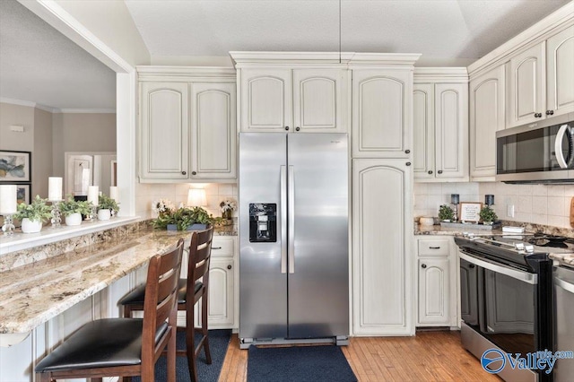 kitchen featuring tasteful backsplash, appliances with stainless steel finishes, light stone countertops, and ornamental molding