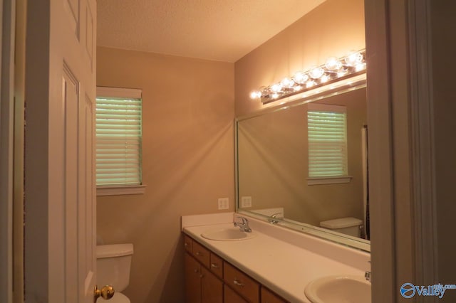 bathroom with vanity, toilet, and a textured ceiling