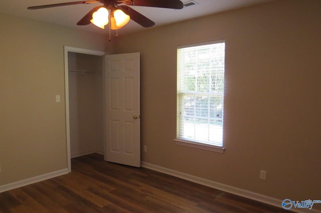 unfurnished bedroom with ceiling fan, dark wood-type flooring, and a closet