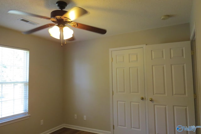 unfurnished bedroom with wood-type flooring, a closet, a textured ceiling, and ceiling fan