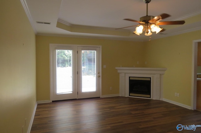 unfurnished living room featuring dark wood-type flooring, a tray ceiling, crown molding, and ceiling fan