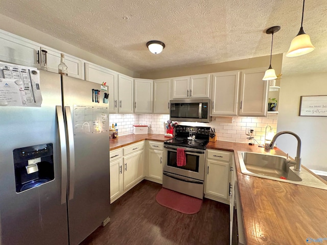 kitchen featuring appliances with stainless steel finishes, butcher block countertops, white cabinetry, and decorative light fixtures