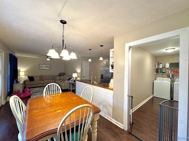 dining room featuring an inviting chandelier, sink, washer and dryer, a textured ceiling, and dark hardwood / wood-style flooring