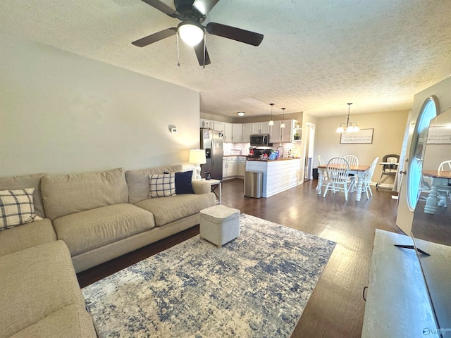 living room featuring ceiling fan with notable chandelier, a textured ceiling, dark hardwood / wood-style floors, and sink