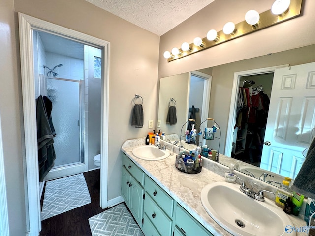 bathroom featuring walk in shower, a textured ceiling, toilet, vanity, and hardwood / wood-style flooring