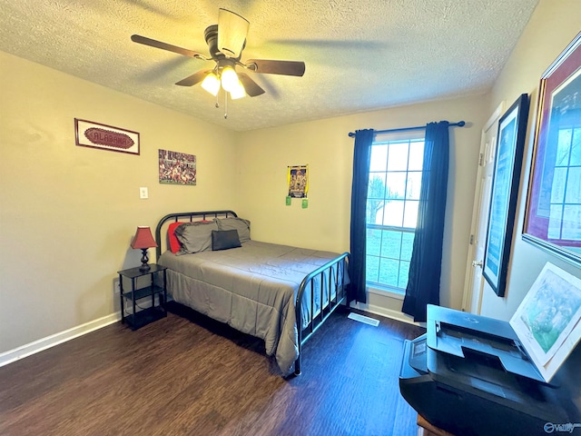 bedroom with a textured ceiling, ceiling fan, and dark hardwood / wood-style floors