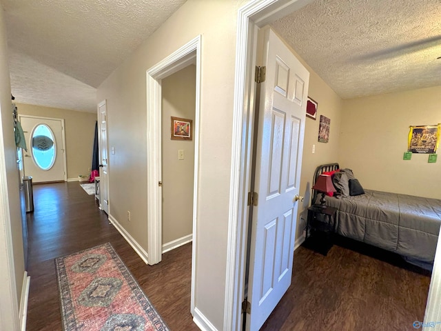 corridor with a textured ceiling and dark hardwood / wood-style floors