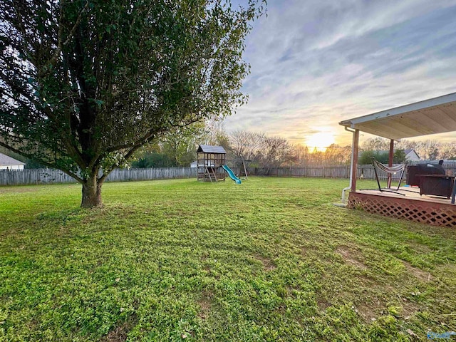 yard at dusk with a playground and a deck