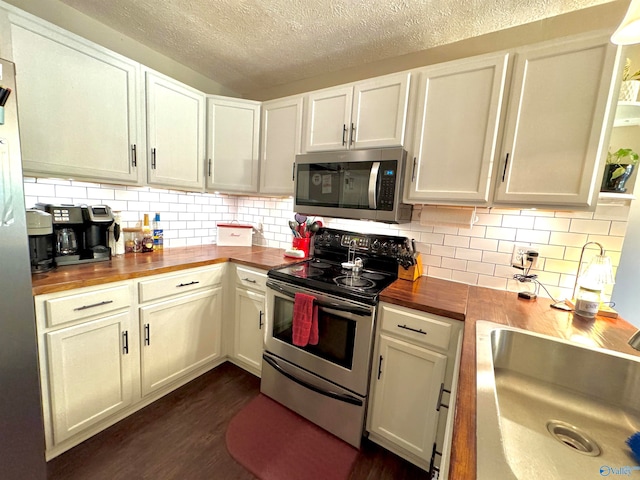 kitchen with wooden counters, stainless steel appliances, dark wood-type flooring, and sink