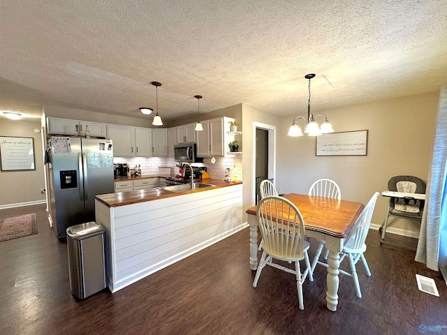 dining space featuring dark hardwood / wood-style floors, sink, a textured ceiling, and an inviting chandelier