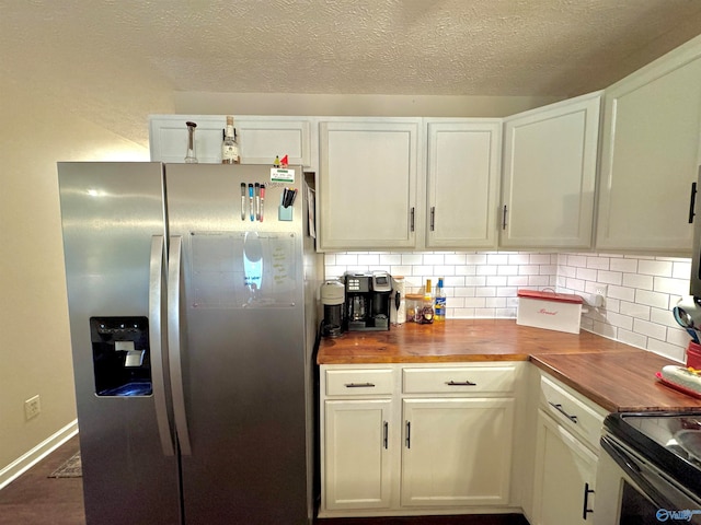 kitchen featuring white cabinetry, butcher block counters, stainless steel fridge, and decorative backsplash