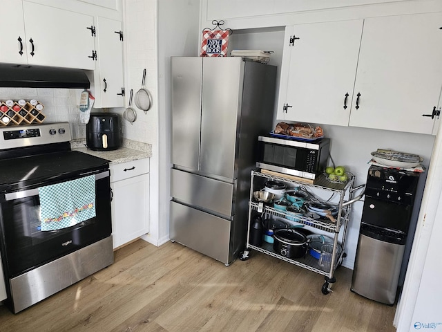 kitchen with white cabinets, appliances with stainless steel finishes, tasteful backsplash, and light hardwood / wood-style flooring