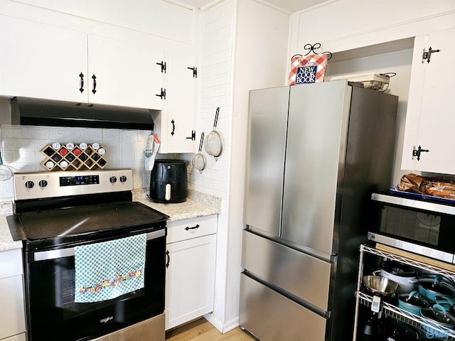 kitchen with backsplash, light hardwood / wood-style flooring, light stone countertops, white cabinetry, and stainless steel appliances