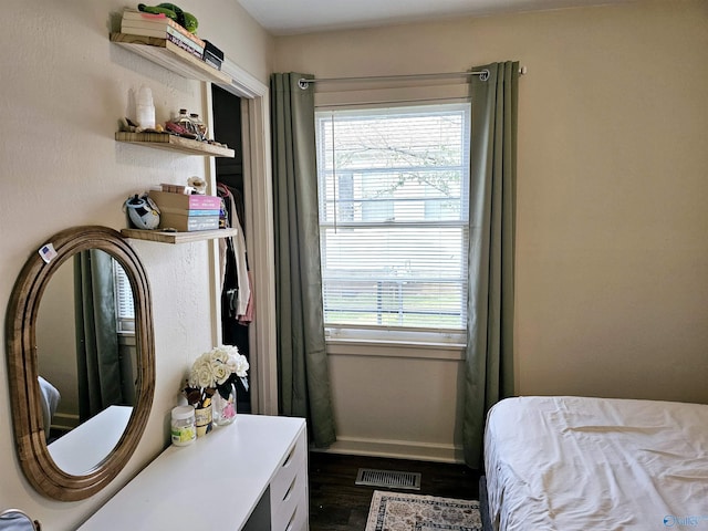 bedroom with multiple windows and dark wood-type flooring