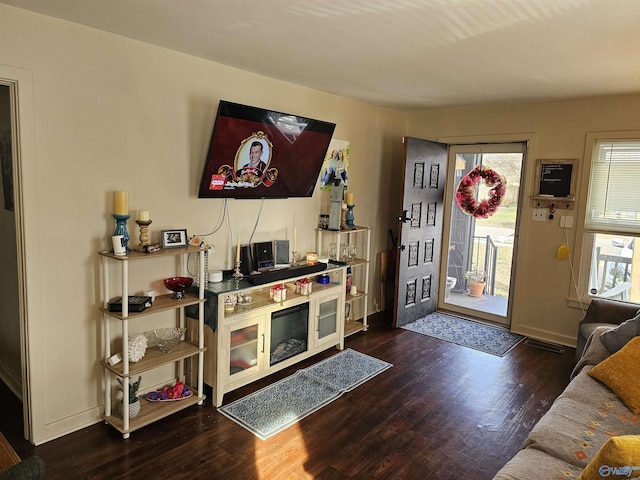 living room with dark hardwood / wood-style flooring and a healthy amount of sunlight