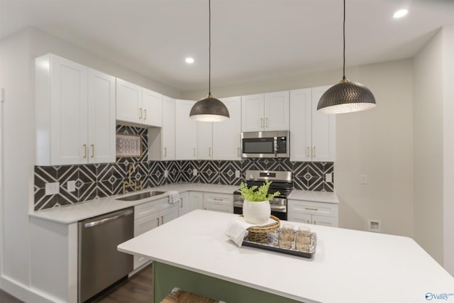 kitchen with decorative light fixtures, stainless steel appliances, and white cabinets