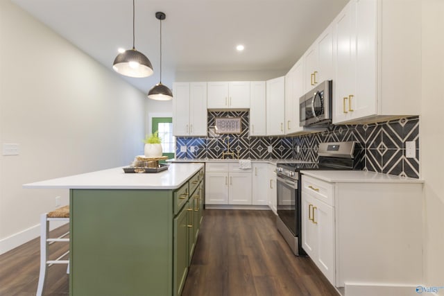 kitchen featuring a kitchen bar, hanging light fixtures, appliances with stainless steel finishes, green cabinets, and white cabinets