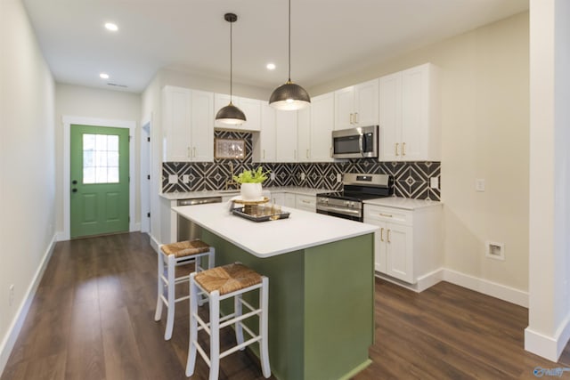 kitchen with white cabinetry, decorative light fixtures, stainless steel appliances, and a kitchen breakfast bar