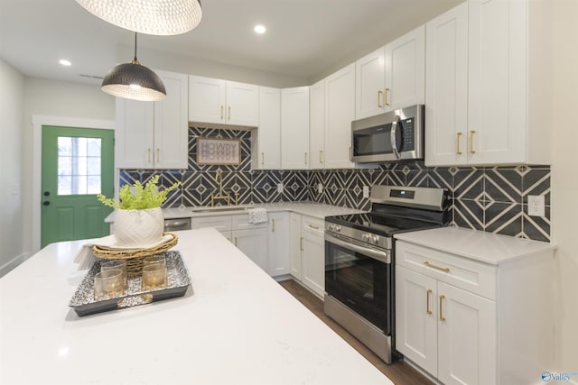 kitchen featuring sink, backsplash, hanging light fixtures, stainless steel appliances, and white cabinets