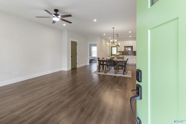 living room with ceiling fan with notable chandelier and dark wood-type flooring