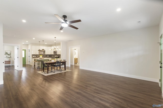 dining space featuring dark wood-type flooring and ceiling fan with notable chandelier