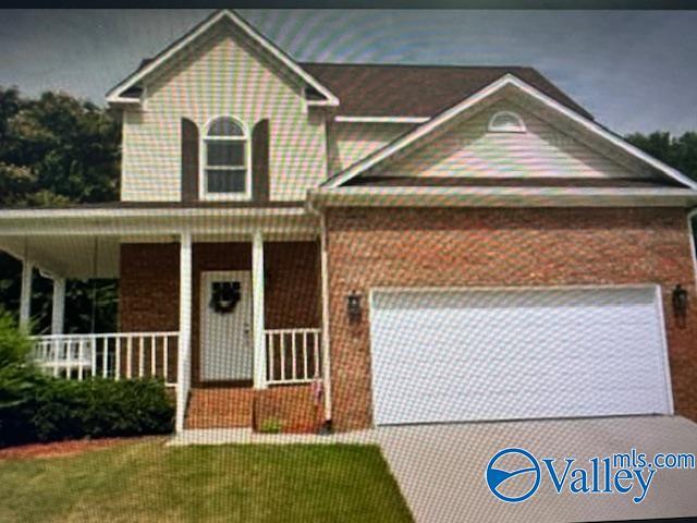 view of front of home featuring a garage, a front lawn, and covered porch