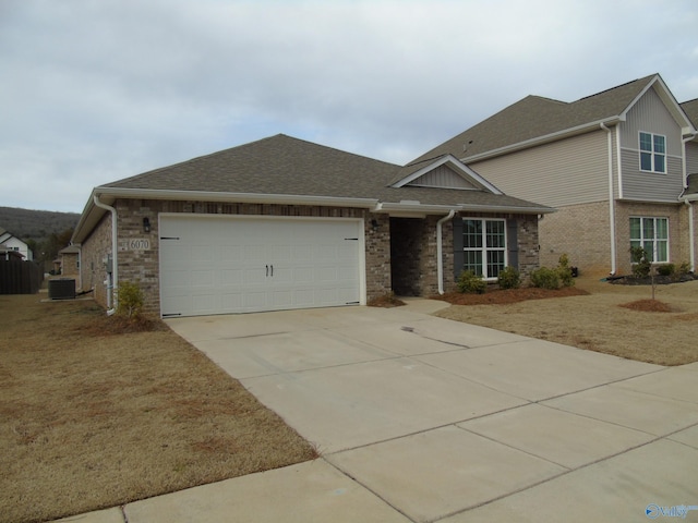 view of front of property featuring cooling unit, concrete driveway, a shingled roof, a garage, and brick siding