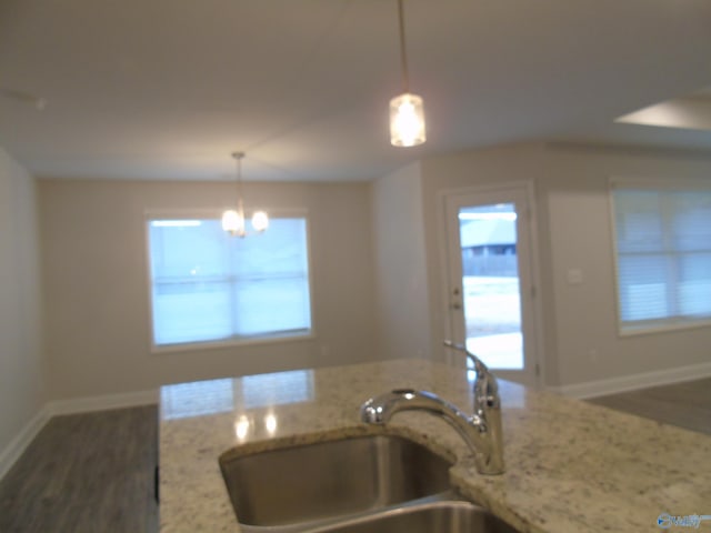 kitchen featuring light stone counters, plenty of natural light, baseboards, and a sink