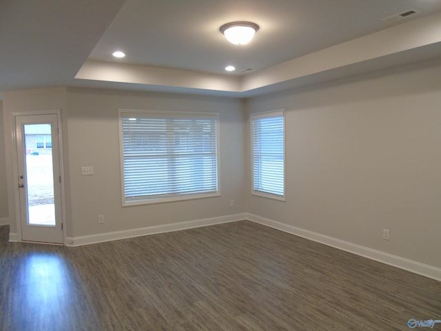 empty room featuring baseboards, visible vents, recessed lighting, dark wood-style flooring, and a raised ceiling