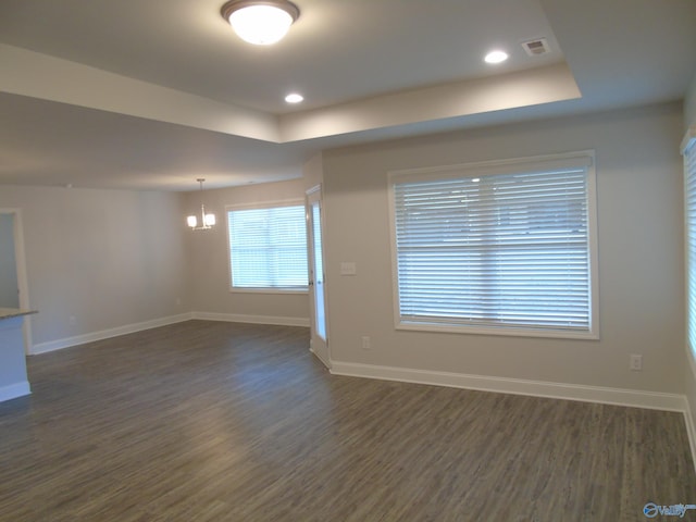 empty room featuring dark wood-style floors, visible vents, and baseboards