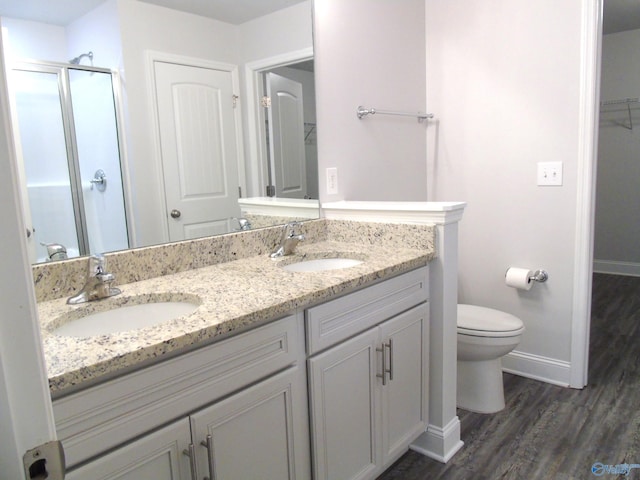 full bathroom featuring double vanity, toilet, a stall shower, and a sink