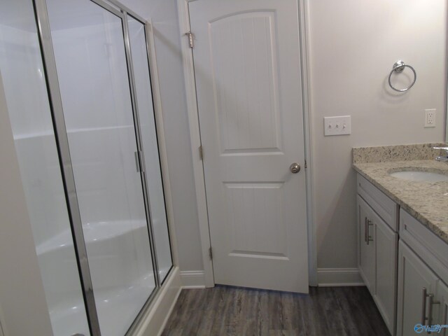 bathroom with a stall shower, vanity, baseboards, and wood finished floors