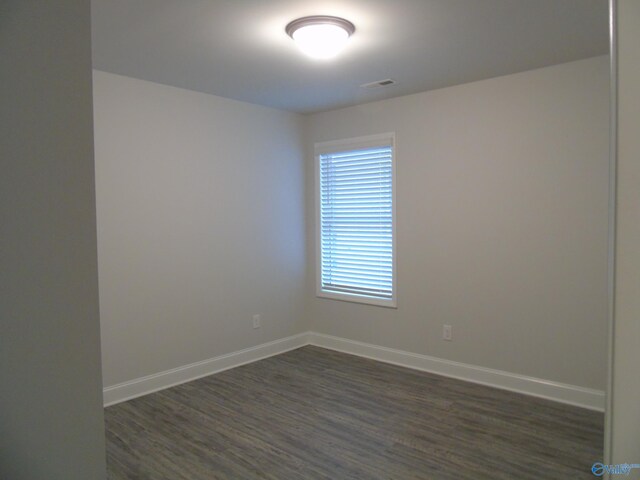 empty room with visible vents, baseboards, and dark wood-style flooring