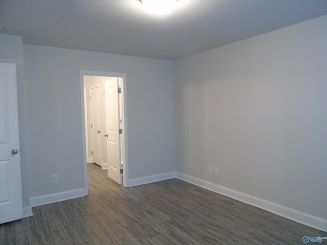 empty room featuring dark wood-style floors and baseboards