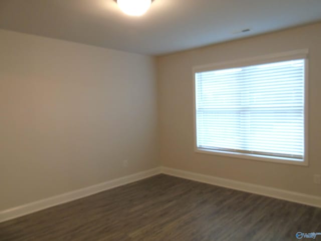 spare room with baseboards and dark wood finished floors