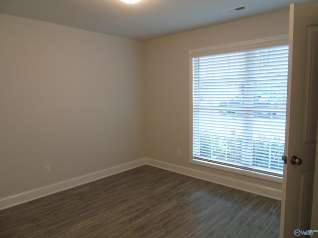 empty room with baseboards, visible vents, and dark wood-style flooring