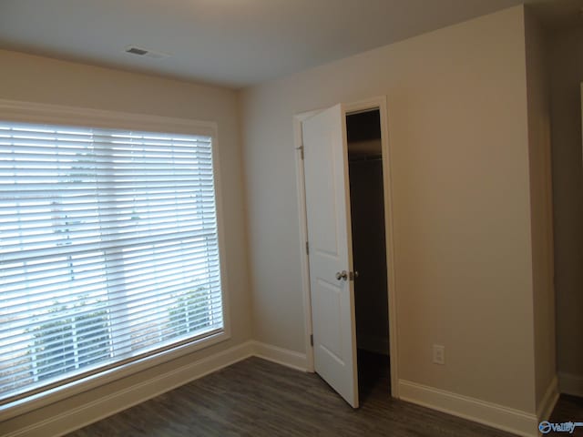 spare room with dark wood-style floors, visible vents, and baseboards