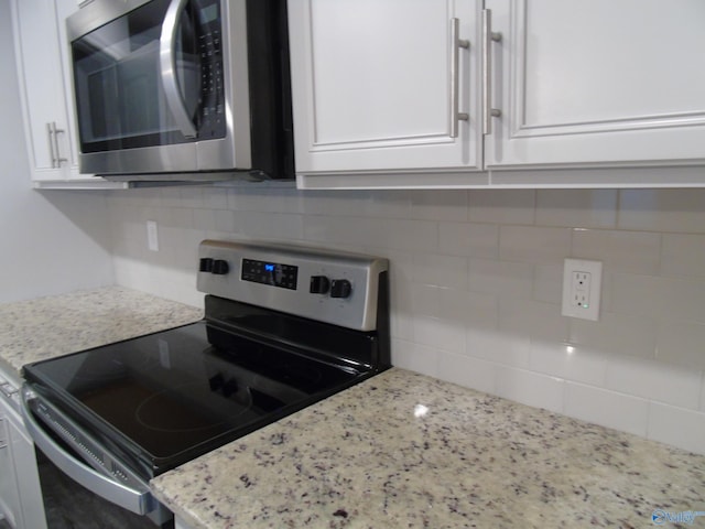 kitchen with stainless steel appliances, light stone countertops, tasteful backsplash, and white cabinetry