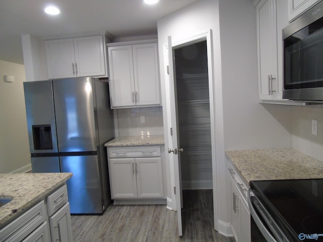 kitchen with tasteful backsplash, light stone counters, recessed lighting, light wood-style flooring, and stainless steel appliances