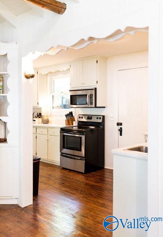 kitchen featuring dark hardwood / wood-style flooring, stainless steel appliances, and white cabinets