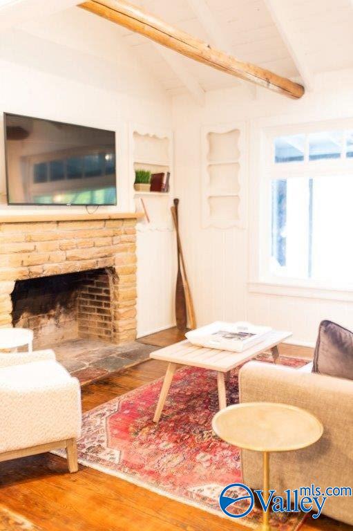 living room featuring vaulted ceiling with beams and wood-type flooring