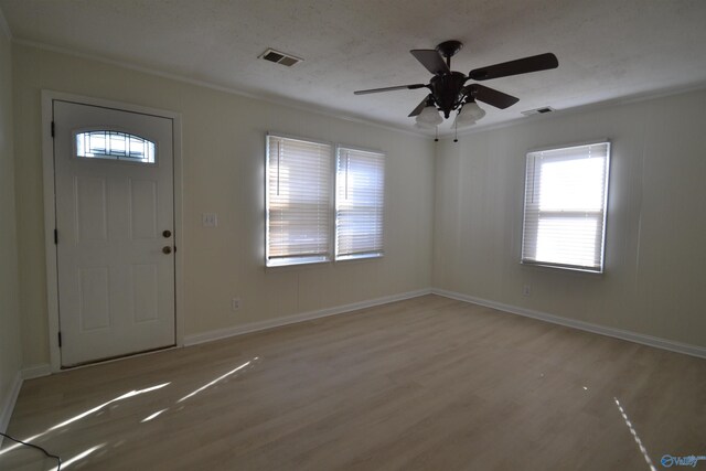 entrance foyer with visible vents, light wood-type flooring, baseboards, and ornamental molding