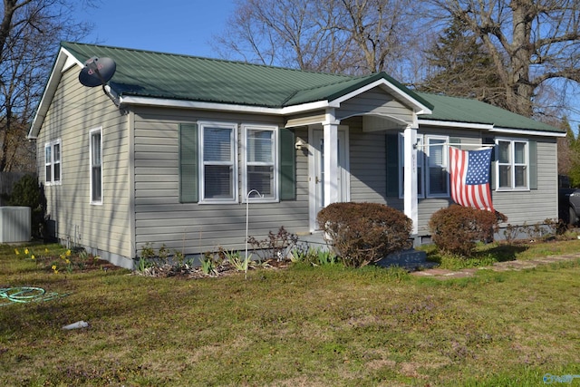 bungalow-style house featuring a front lawn, central AC, and metal roof