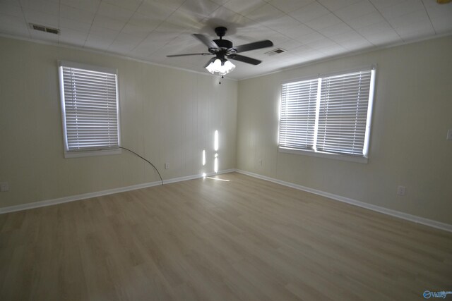 empty room with baseboards, wood finished floors, visible vents, and ornamental molding