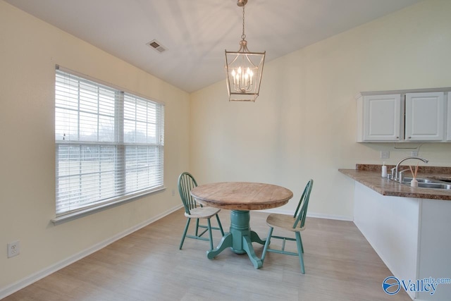 dining space with lofted ceiling, visible vents, an inviting chandelier, light wood-style floors, and baseboards