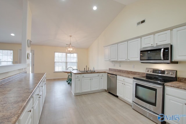 kitchen featuring stainless steel appliances, a peninsula, a sink, visible vents, and white cabinets