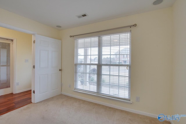 carpeted empty room featuring a wealth of natural light, visible vents, and baseboards