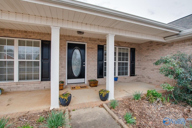 property entrance with a porch and brick siding