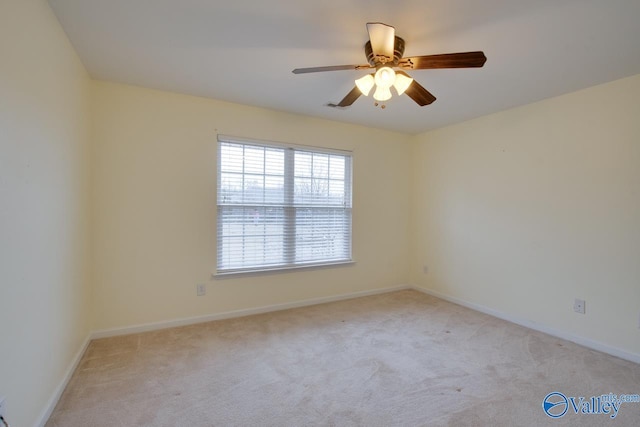 spare room with light carpet, ceiling fan, and baseboards